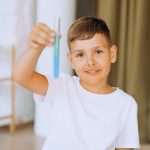 Smiling child holding test tube during a science experiment at home.