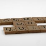 Scrabble tiles spelling 'Commit Or Quit' on a white surface, symbolizing decision-making.